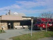 A senior center with a red bus parked in front of it.